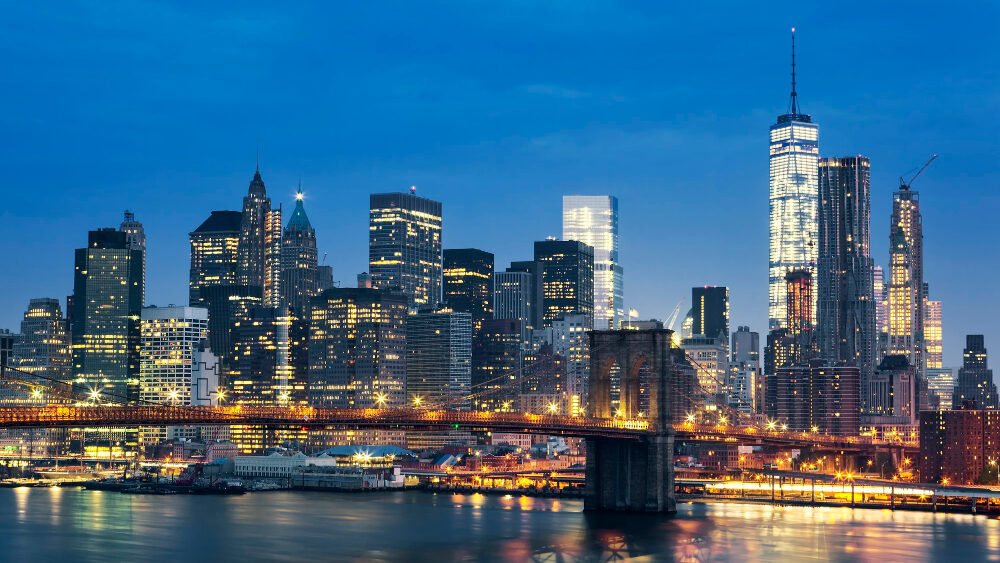 Evening cityscape view of New York City skyline featuring illuminated skyscrapers and the Brooklyn Bridge over the East River, a scene that reminds residents to consider reliable pest control in New York to maintain their urban oases